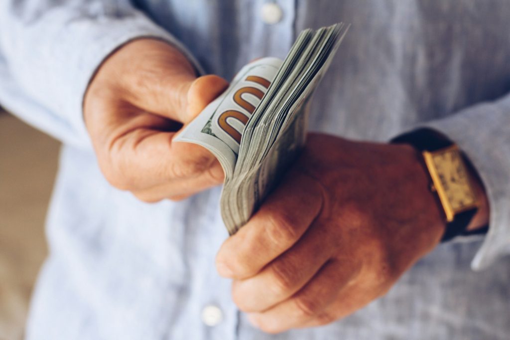 Hombre con dinero en la mano-¿Es Posible Realizar un Injerto Capilar sin Rapar el Cabello?-UVEMedical, ser una clinica pionera en injertis capilares y otros tratamientos esteticos
