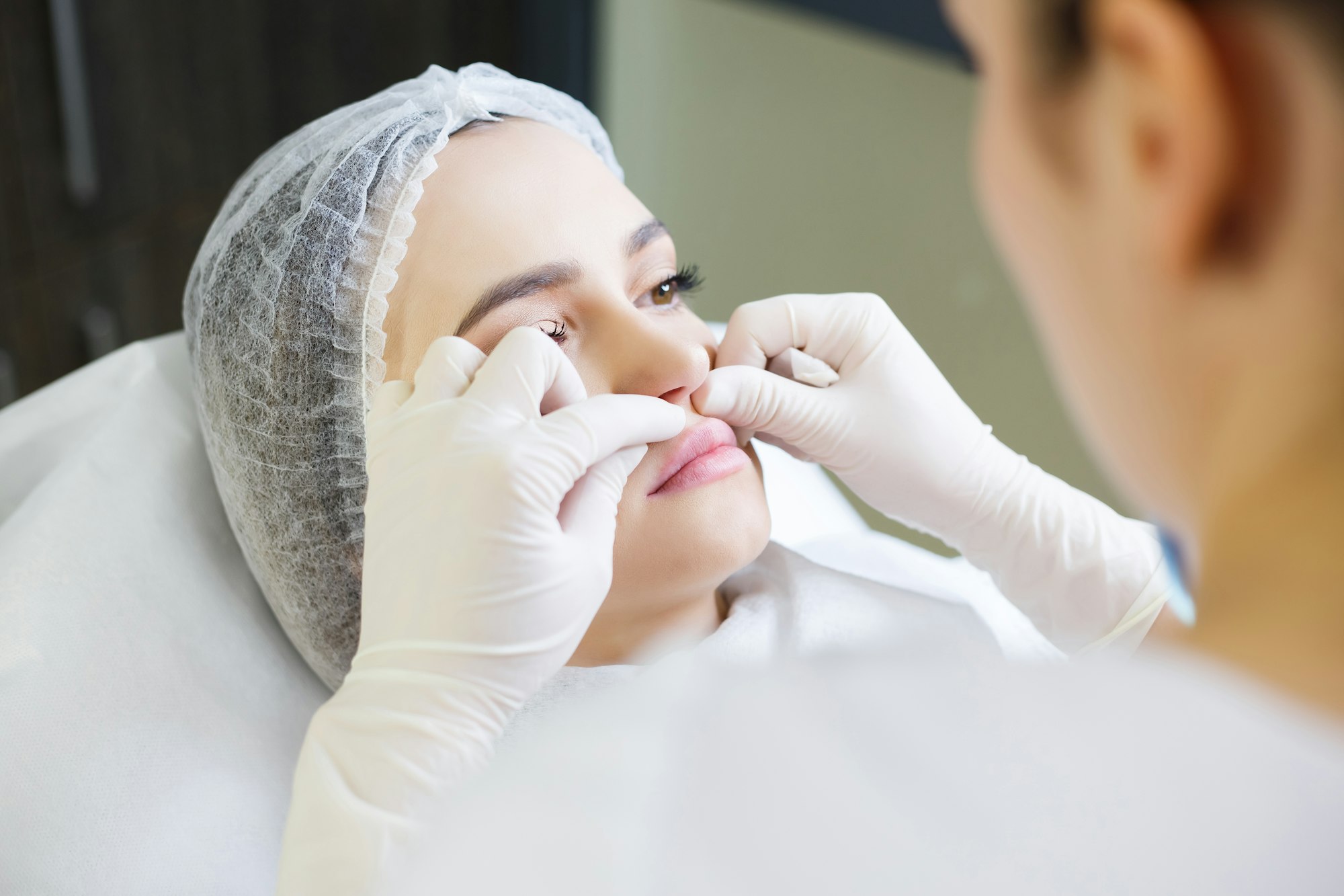 Doctor man with white medical gloves touches girl face.